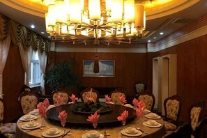 Une salle de conférence dotée d’une table ronde, agrémentée de compositions florales et illuminée par de somptueux lustres.