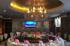 A conference room with a round table, chairs, a chandelier, and a television on the wall. - Shuang Bai Hotel (Shuangbai)