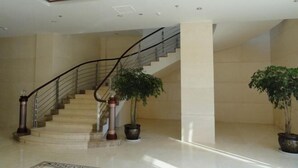A modern interior with a marble staircase, a large column, and potted plants. - Shuang Bai Hotel (Shuangbai)