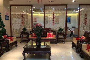 Un vestíbulo de estilo tradicional con muebles de madera, una mesa de centro de vidrio y plantas decorativas.