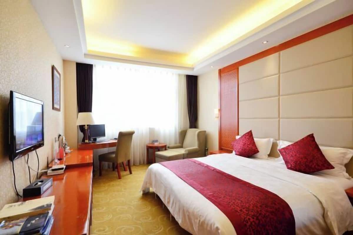 Una habitación de hotel con una cama, un escritorio, un televisor y una silla.