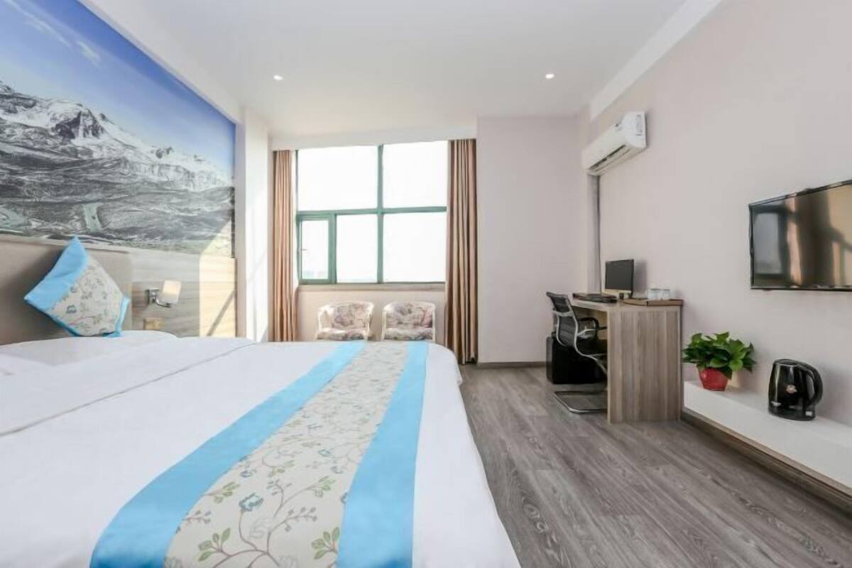 Ein Hotelzimmer mit Bett, Schreibtisch, Fernseher und Fenster.