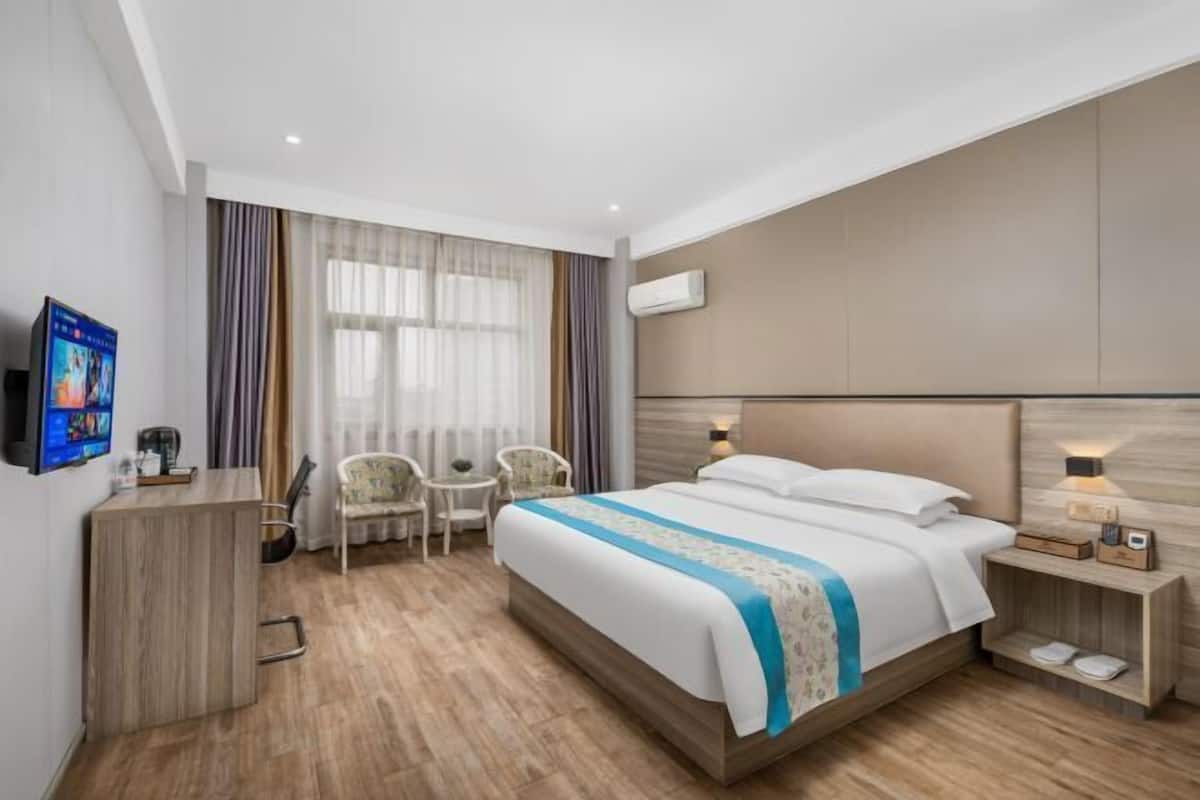 Ein Hotelzimmer mit Bett, Nachttisch, Stuhl, Schreibtisch und Fernseher.