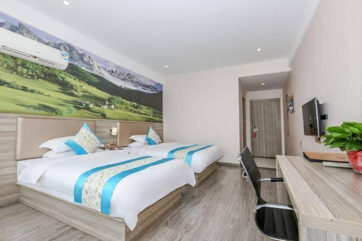 Ein Hotelzimmer mit zwei Betten, einem Schreibtisch und einem großen Wandbild.