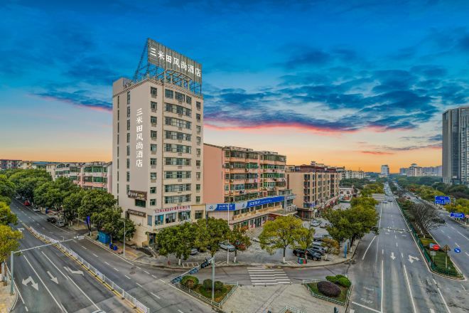 A multi-story hotel with a modern design, located at a city intersection with wide roads and greenery.