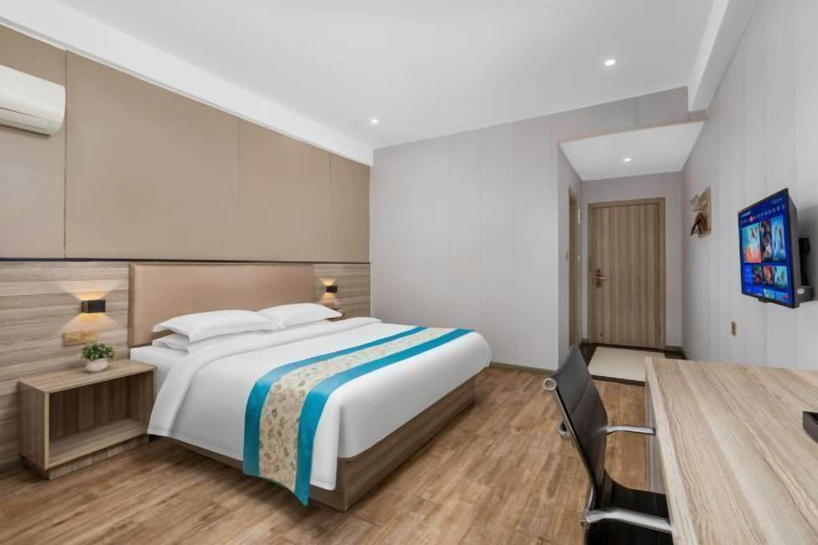 Ett modernt hotellrum med en stor säng, sängbord, ett skrivbord och en tv.