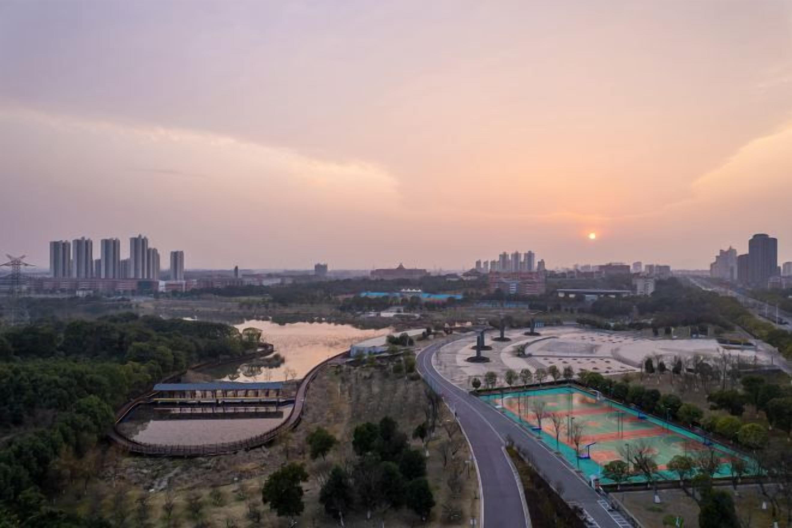A cityscape with a river, a bridge, and a sports field.