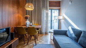 Una sala moderna con sofá, televisión, mesa de comedor y sillas.