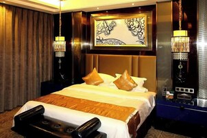 A hotel room with a large bed, a mirror, and two wall-mounted lamps.