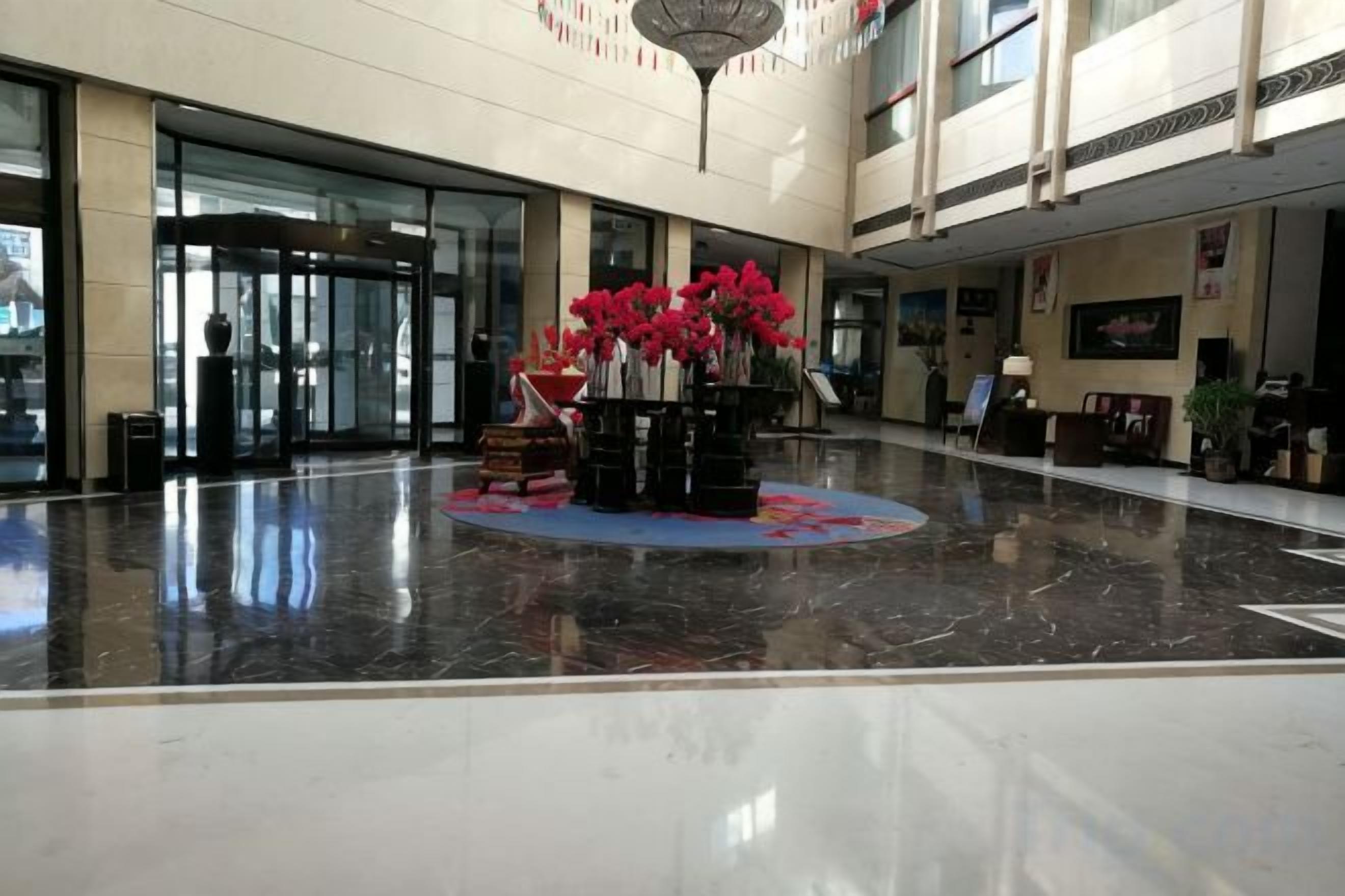 A spacious lobby with a marble floor, a reception desk, and a decorative centerpiece with flowers.