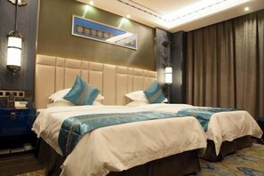 A hotel room with two beds, a headboard, wall-mounted lamps, a painting, and a curtain.