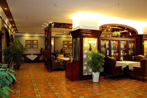 A hotel lobby with a checkered floor, a reception desk, and a seating area with tables and chairs. - Shandong Building (Shigatse)