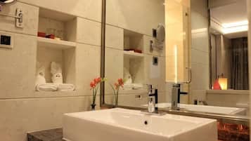A bathroom with a large mirror, a white sink, and a marble countertop.