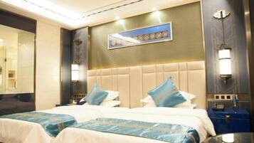 A hotel room with a large bed, a headboard with a decorative panel, and a wall-mounted artwork.