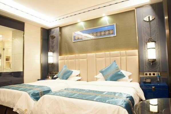A hotel room with a large bed, a headboard with a decorative panel, and a wall-mounted artwork.