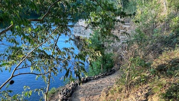 A stone pathway leading to a body of water, surrounded by trees and vegetation. - Riverside open space concept cabin @ Riverhill (Cristo Rey)