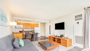 A modern living room with a grey sofa, a glass coffee table, and a wooden TV stand.