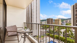 A balcony with a table, chairs, and a bottle of champagne.