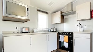 Una cucina compatta con mobili bianchi, un forno a microonde, un forno e un lavello.