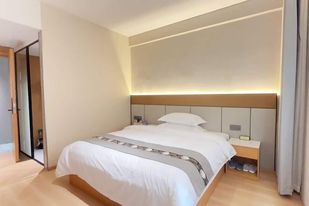 Ein Hotelzimmer mit Bett, Nachttisch und Schuhablage.