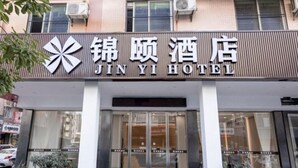 Entrada de um hotel com uma placa que diz 'JIN YI HOTEL'.