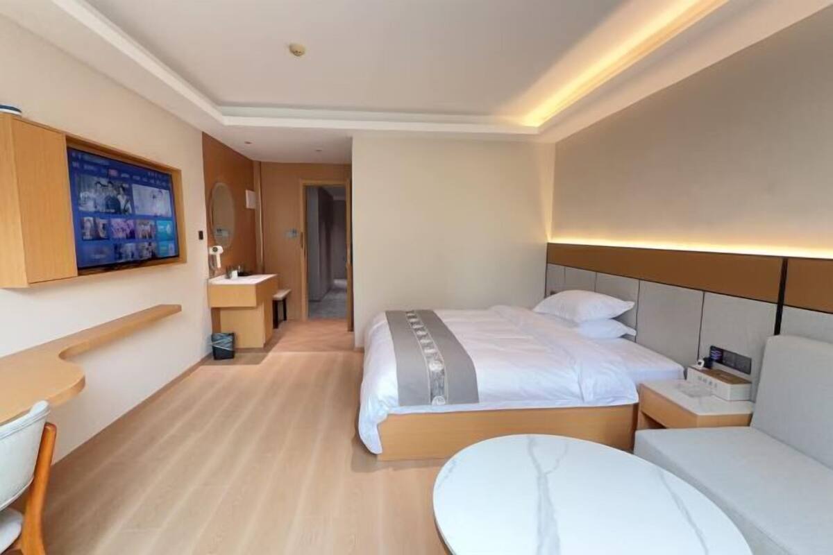 Ein Hotelzimmer mit Bett, Nachttischen, Schreibtisch, Stuhl, Fernseher und Bad.