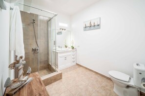 Une salle de bain moderne avec une douche à parois de verre, un meuble-lavabo en bois, des toilettes blanches et un lavabo fixé au mur.