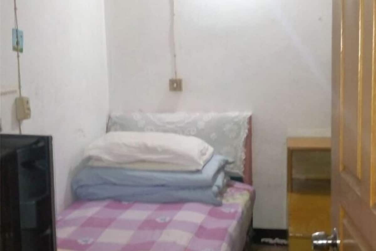A small room with a bed, a television, and a wooden door.
