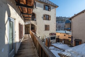A narrow wooden pathway leading to a building with multiple windows and a balcony. - Rustic-Chic in a paradise of sports and nature! (Briançon)