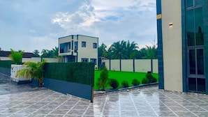 A modern building with a flat roof, a green wall, and a tiled patio area. - Northwold Hotel-Sowutuom Accra (Accra)