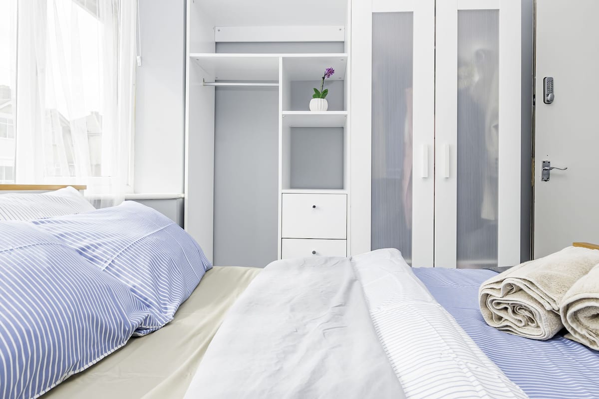Een hotelkamer met een bed, een garderobe en een kleintje tafeltje met een bloevas.