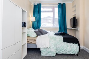 A bedroom with a bed, a TV, a window with curtains, and a wardrobe. - Shirley House 3 Guest House Self Catering  (Southampton)