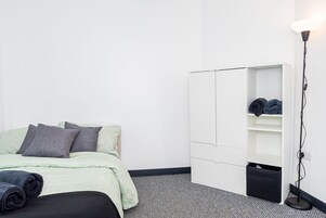 Quarto minimalista com cama, guarda-roupa e abajur.