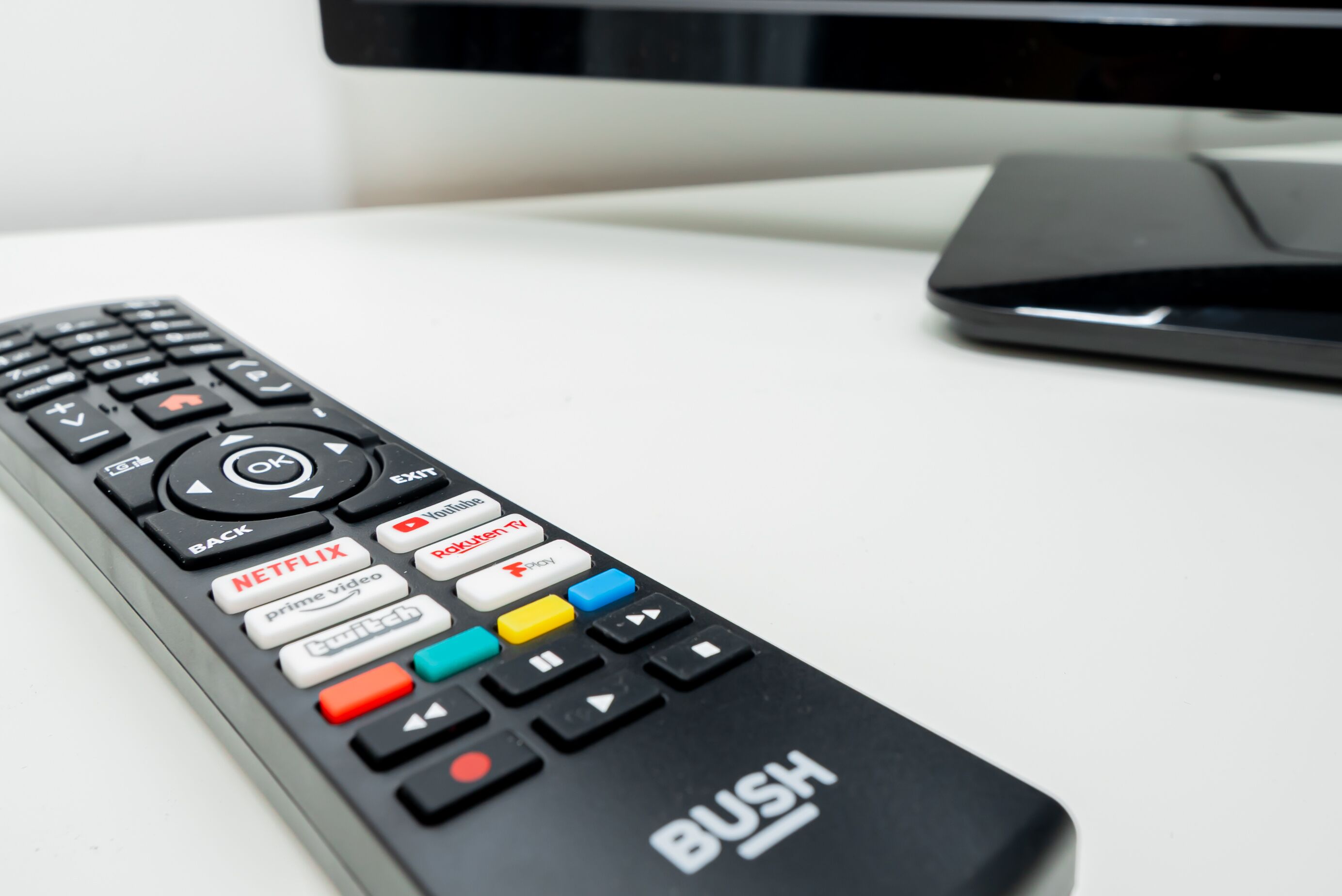 En sort fjernbetjening med mærkede knapper, inklusive “Netflix”, “Prime Video” og “Roku”.