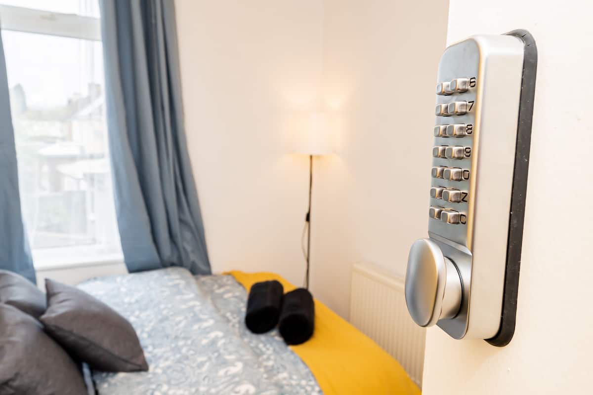 Een kamer met een bed, een bedieningspaneel aan de muur en een raam met gordijnen.