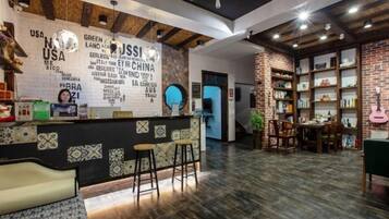 Un área de recepción con mostrador, taburetes de bar y una pared con texto y logotipos.