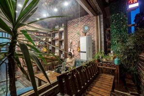 A cozy interior with a wooden bench, bookshelves, and potted plants. - Dream 1988 Hotel (Zhangjiajie)