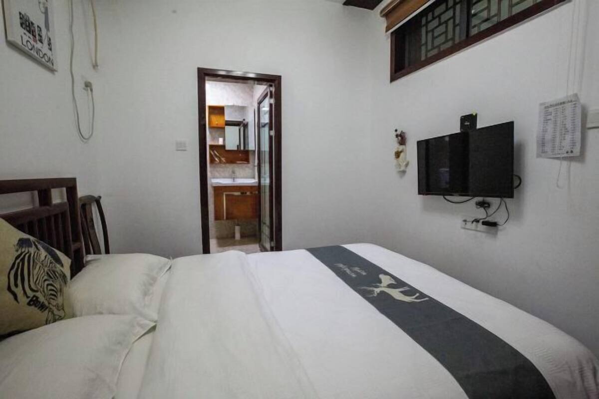 Een hotelkamer met een bed, een aan de muur bevestigde televisie en een deur naar een badkamer.