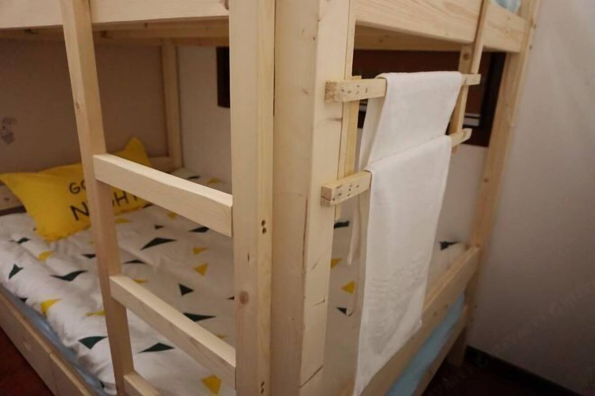 Een stapelbed met een witte matras en een geel kussen.