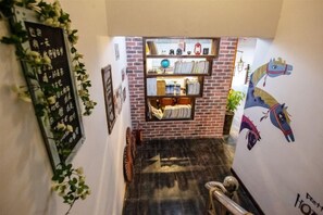 A staircase with a brick wall and a shelf with various items. - Dream 1988 Hotel (Zhangjiajie)
