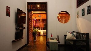 Un intérieur chaleureux comprenant un coin repas, un miroir rond et un espace salon avec une table et un banc.