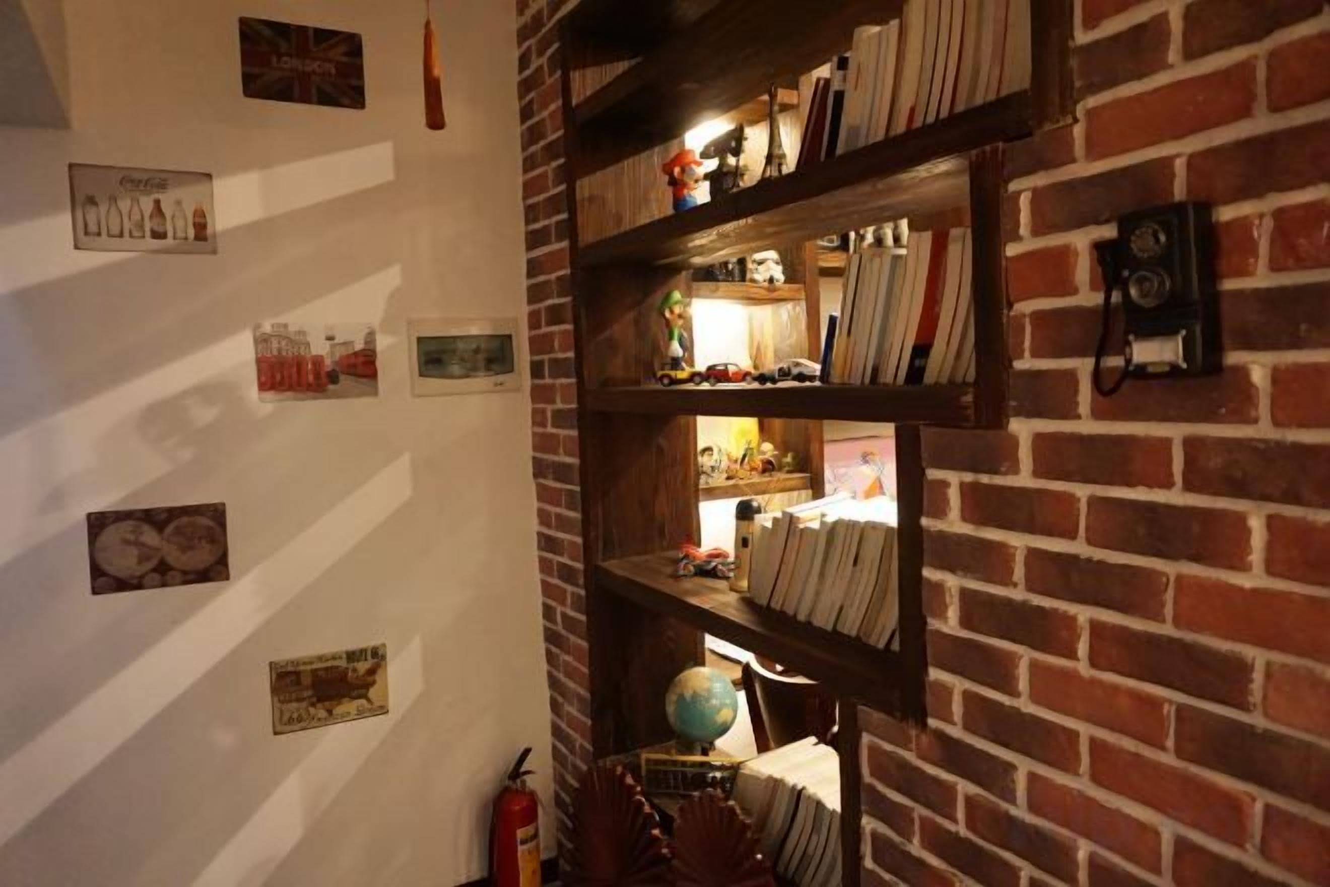 Una pared de ladrillo con estantes que contienen libros y objetos decorativos.