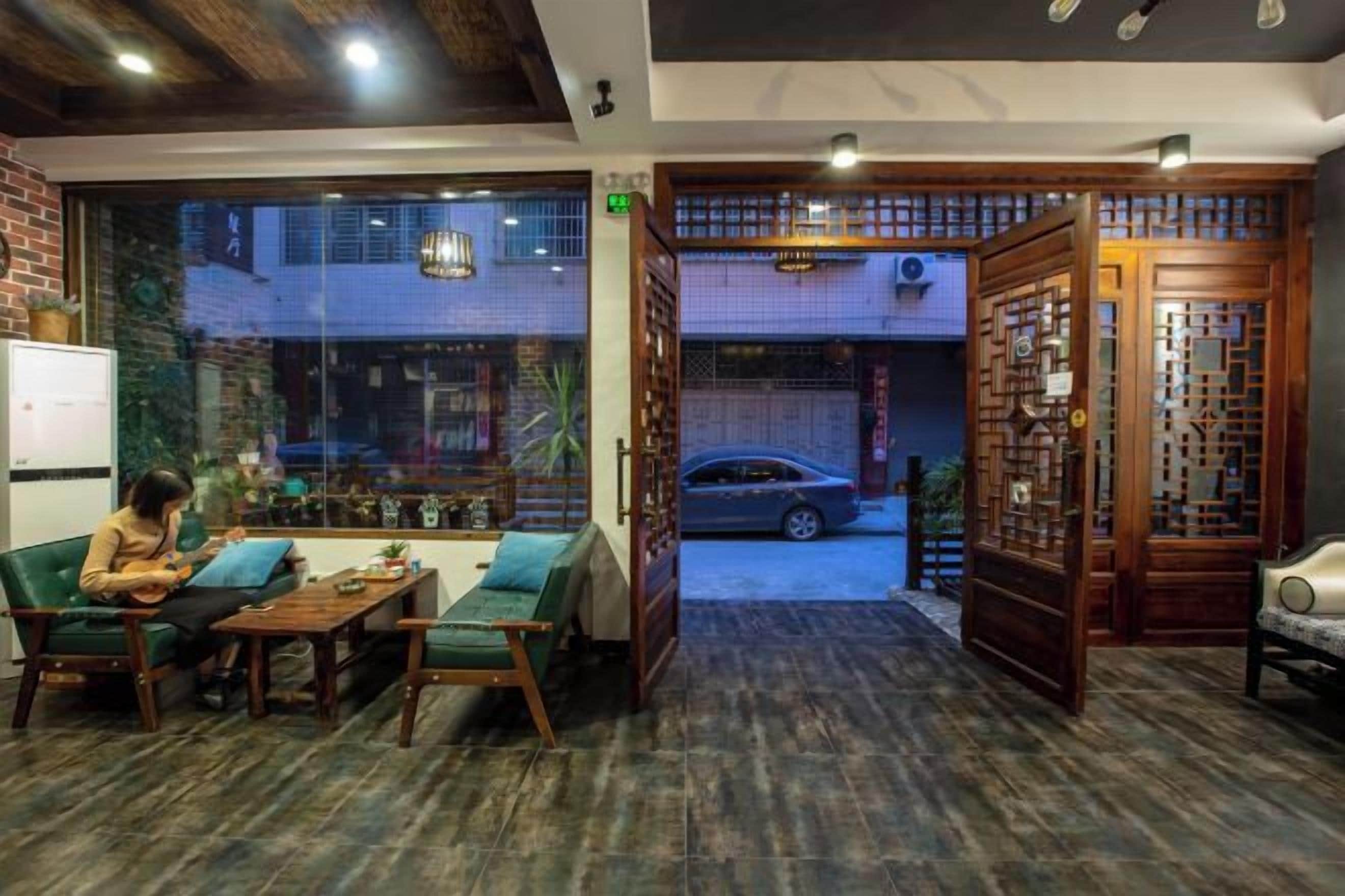Un interior acogedor con un sofá, una mesa y sillas, vista a través de un vidrio y un tradicional separador de madera.
