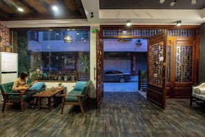 A cozy interior with a sofa, table, and chairs, a view through a glass door, and a traditional wooden partition.