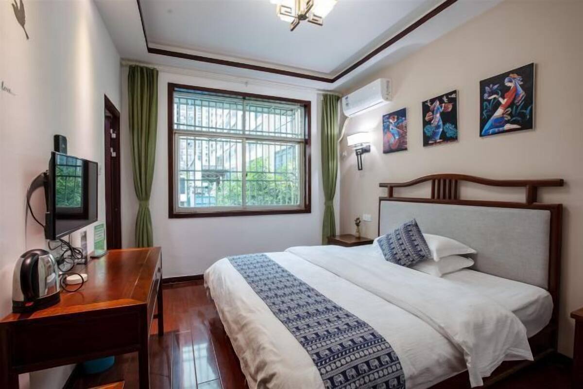 Een hotelkamer met een bed, een bureau met een computer, een televisie en kunst aan de muur.