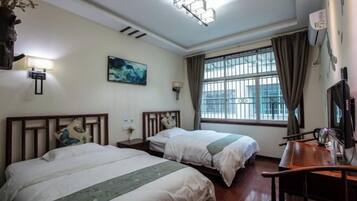 Habitación de hotel con dos camas, un escritorio, una silla, un ventanal con cortinas, un televisor montado en la pared y un cuadro.