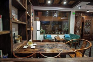 Uma área de refeições com mesa e cadeiras de madeira, um sofá e uma janela com vista.