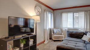 A living room with a flat-screen TV, a lamp, a sofa, and a chair.