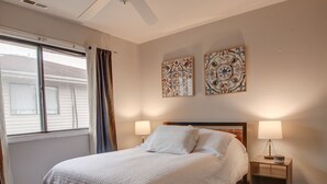 A neatly made bed with a white quilt, two bedside lamps, and two wall-mounted artworks.