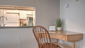 A wooden desk with a chair, a potted plant, and a sign with wifi password.